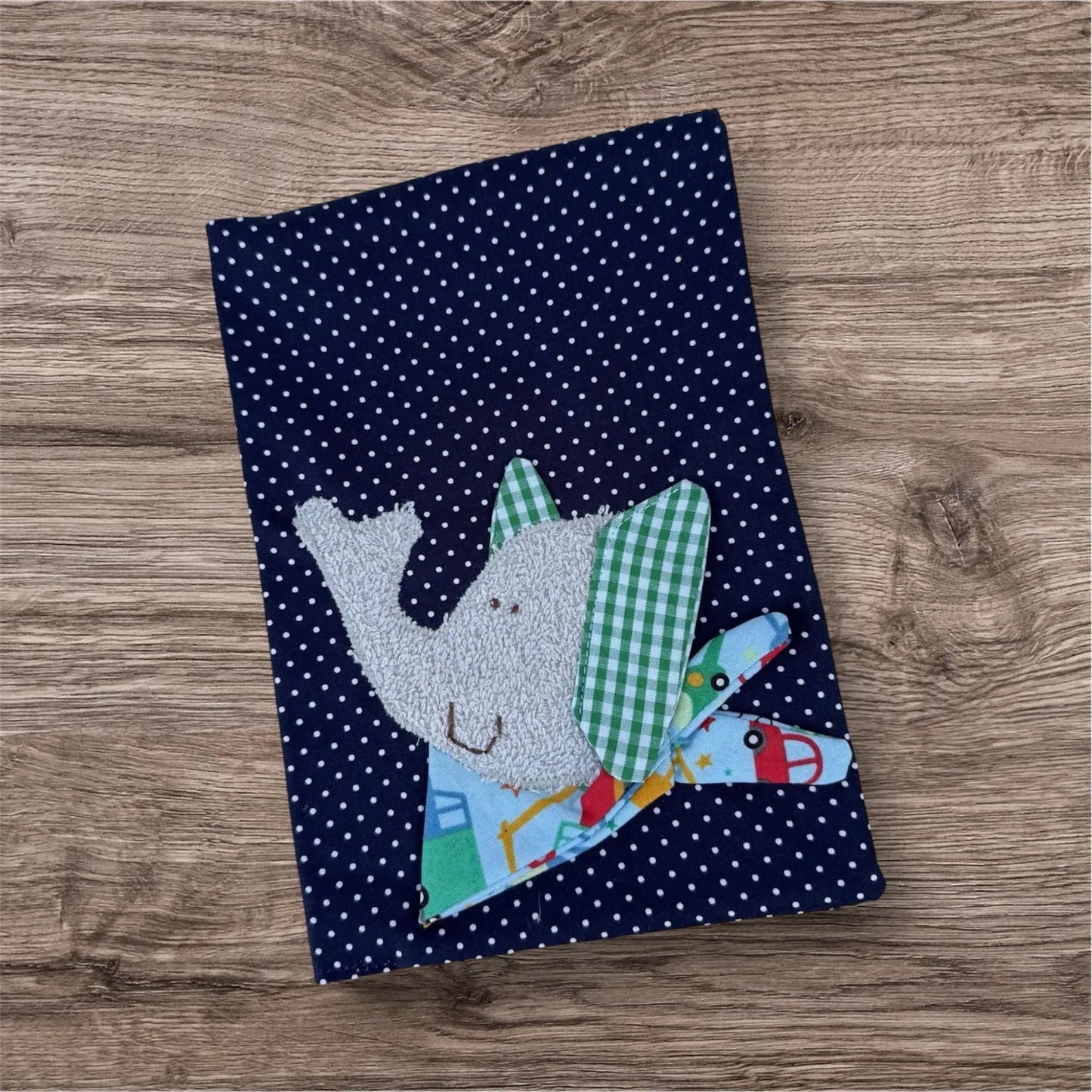 Personalisierbare U-Heft-Hülle aus dunkelblauen Stoff mit weißen Punkten , verziert mit einem fröhlichen Elefant und personalisierbar mit Namen