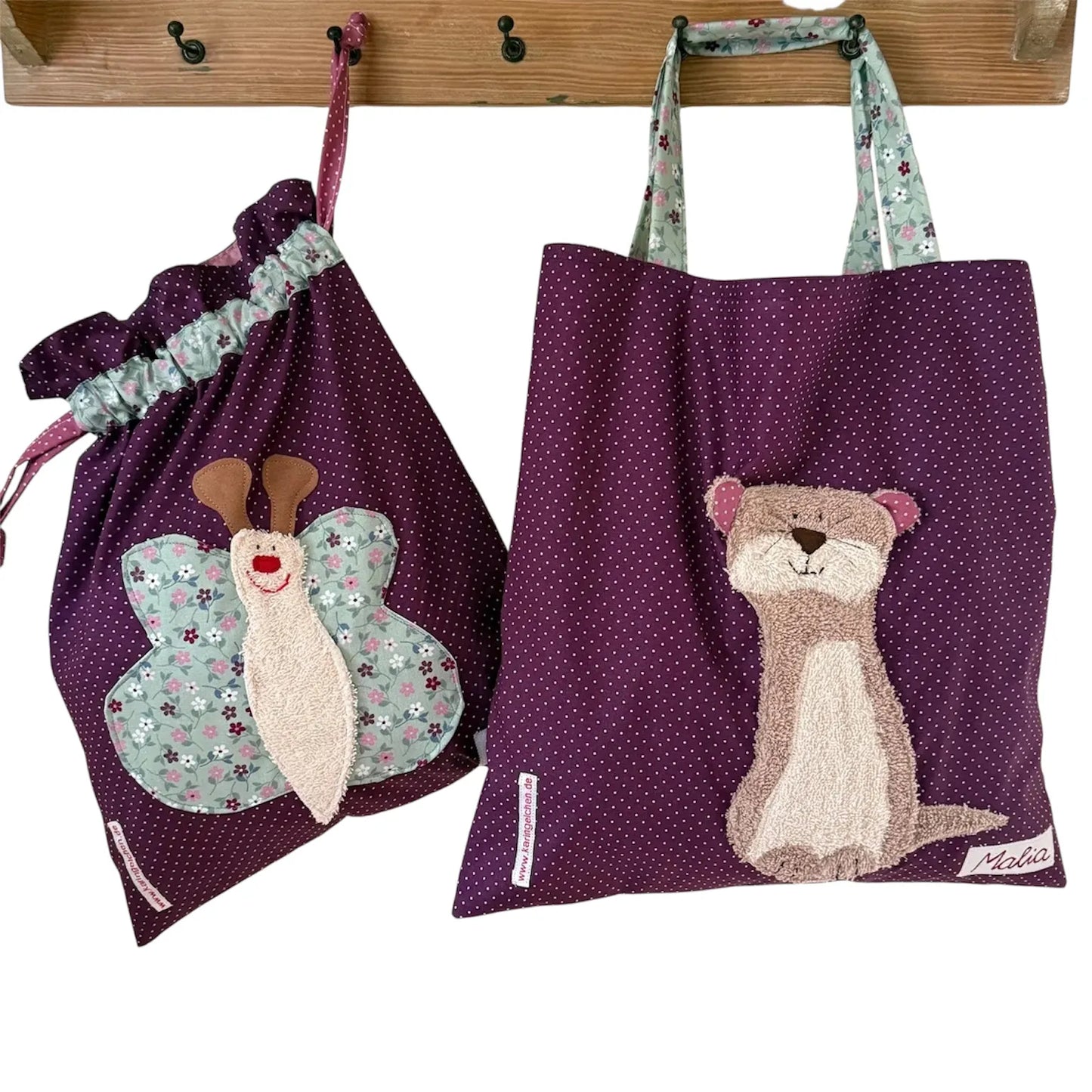 Handgemachtes Kita-Set bestehend aus einem dunkellila Wetbag mit Schmetterlingsmotiv und einem passenden Garderobenbeutel mit Otterapplikation beide aus gepunkteten Stoff mit bunten Details
