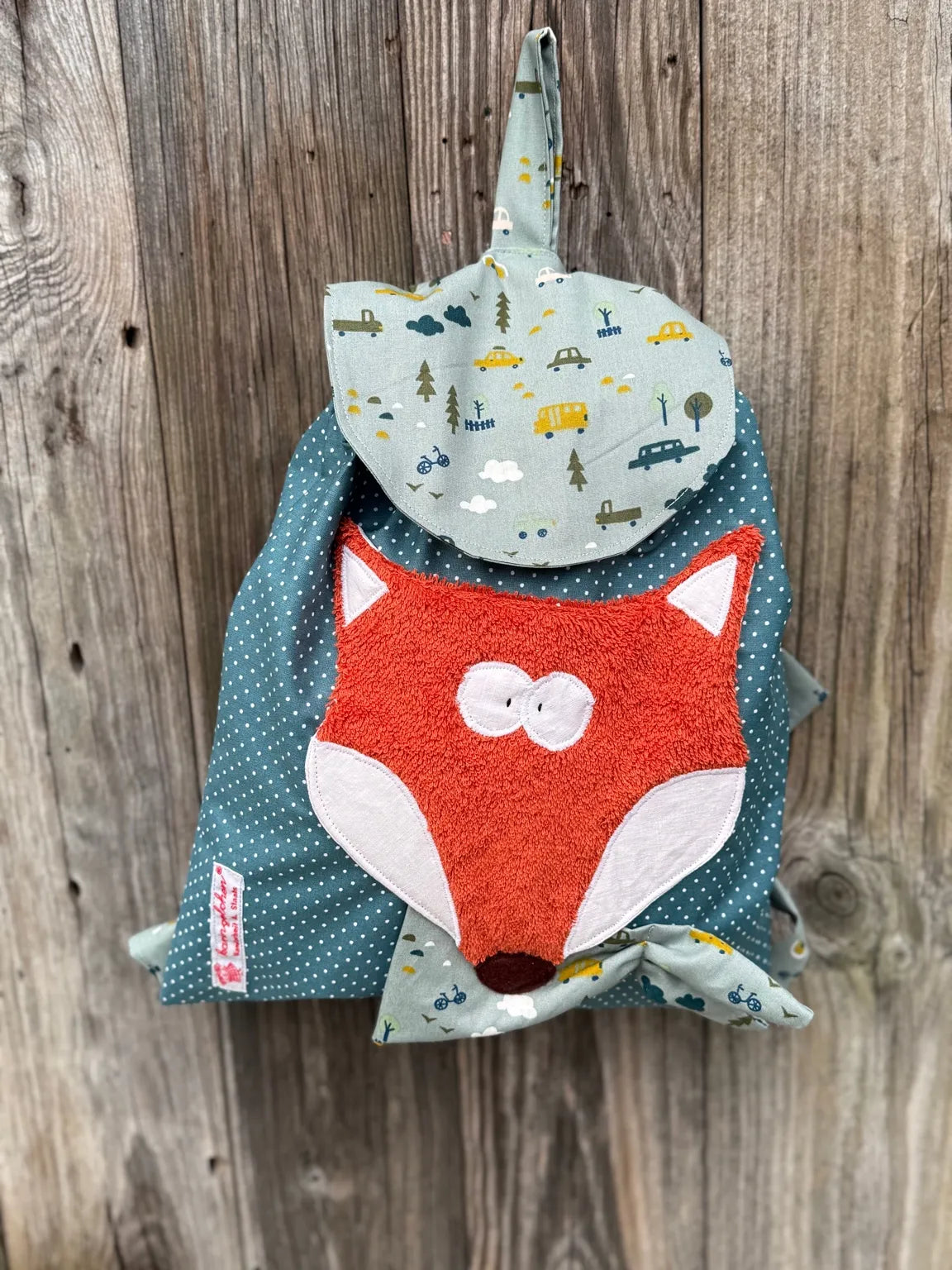 Handgemachter Kinderrucksack ist
grünmit weißen Punkten ,
hat eine altmint Klappe mit Autoprint und eine aufgenähte Applikation eines
orangefarbenen Fuchses.