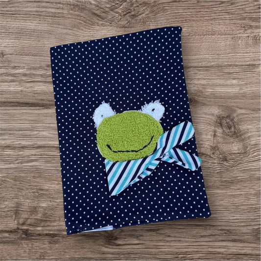 Personalisierbare U-Heft-Hülle aus dunkelblauen Stoff mit weißen Punkten , verziert mit einem fröhlichen Frosch und personalisierbar mit Namen
