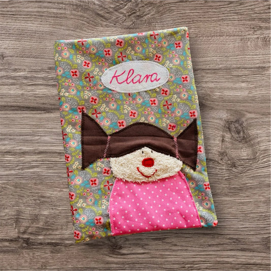Personalisierbare U-Heft-Hülle aus beigem Stoff mit bunten Blümchen , verziert mit einem fröhlichen Mädchen und Personalisierbar  mit Namen