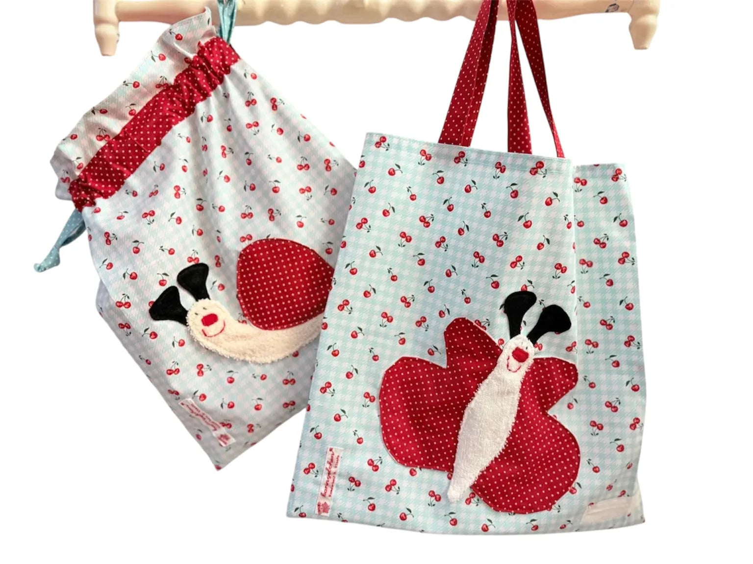 Handgemachtes Kita-Set bestehend aus einem mintgrün karierten Wetbag mit Schneckenmotiv und einem passenden Garderobenbeutel mit Schmetterlingsapplikation-beide aus 
 Stoff mit Kirschprint und bunten Details