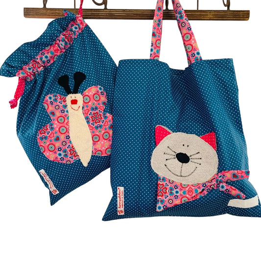 Handgemachtes Kita-Set bestehend aus einem blauen Wetbag mit Schmetterlingsmotiv und einem passenden Garderobenbeutel mit Katzenapplikation- beide aus gepunkteten Stoff mit bunten Details