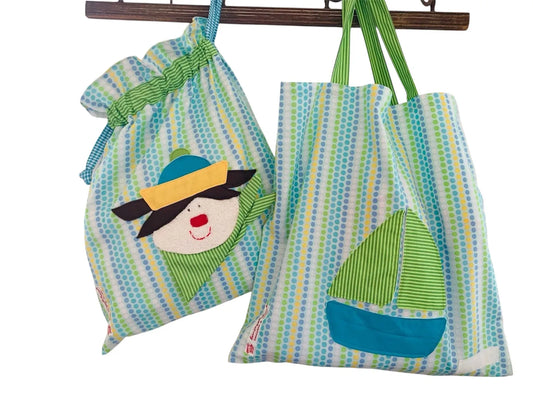 Handgemachtes Kita-Set bestehend aus einem blau grüner Wetbag mit Matrosenmotiv und einem passenden Garderobenbeutel mit Bootsapplikation beide aus gepunkteten Stoff mit bunten Details