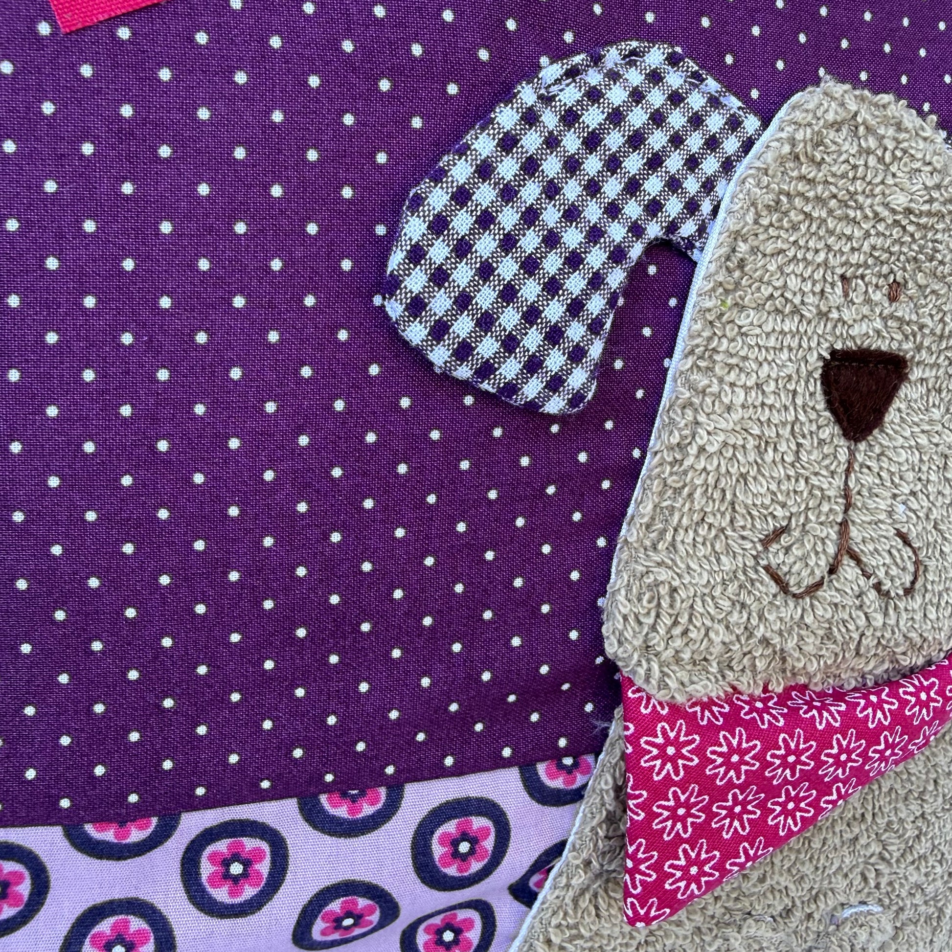 Lila personalisiertes Kinderkissen mit Namen Mira und Hund-Applikation aus Frottee, handgenäht aus Baumwolle im farbenfrohen Mustermix, 40x40 cm Kuschelkissen für Mädchen
Seitliche Nahaufnahme der kuscheligen Hundeapplikation