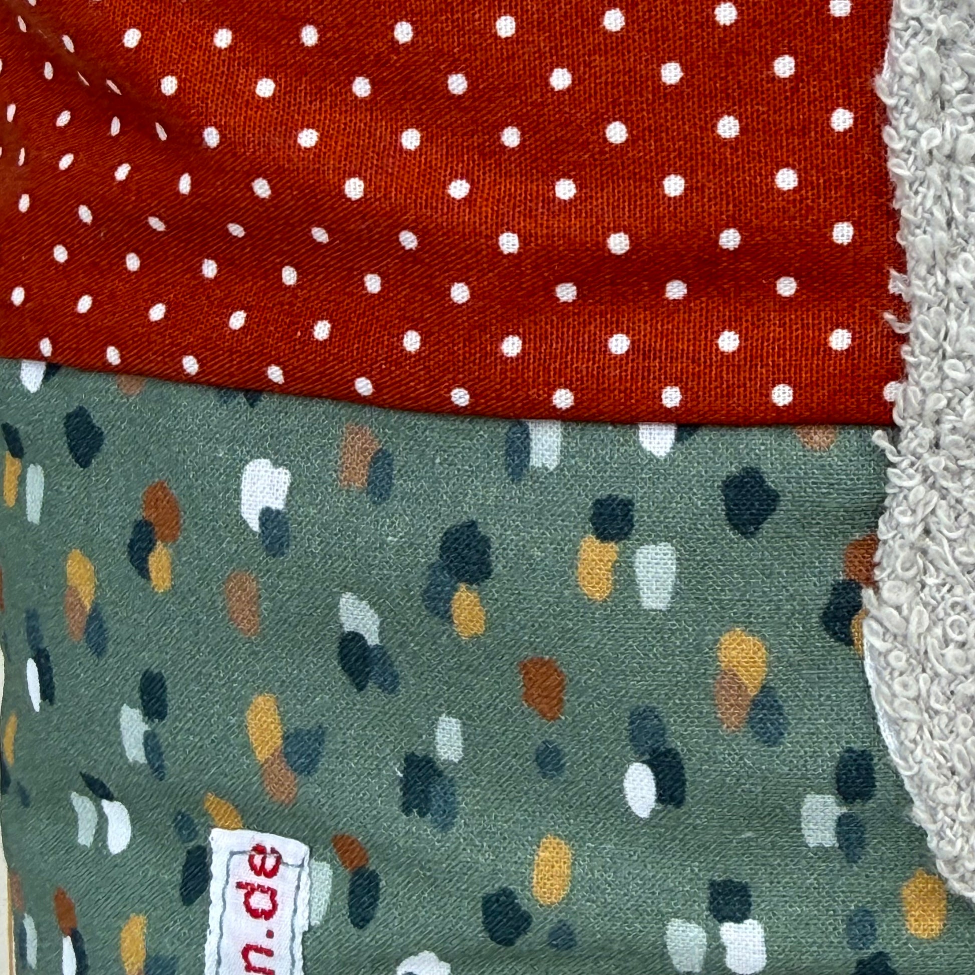 Personalisiertes Kinderkissen mit Elefant und Namen, Rost rot gepunkteter Baumwollstoff und Salbei getupften Baumwollstoff mit 3D-Frottee-Applikation in Blau und Grau, handgemacht.
Nahaufnahme der Stoffkombi