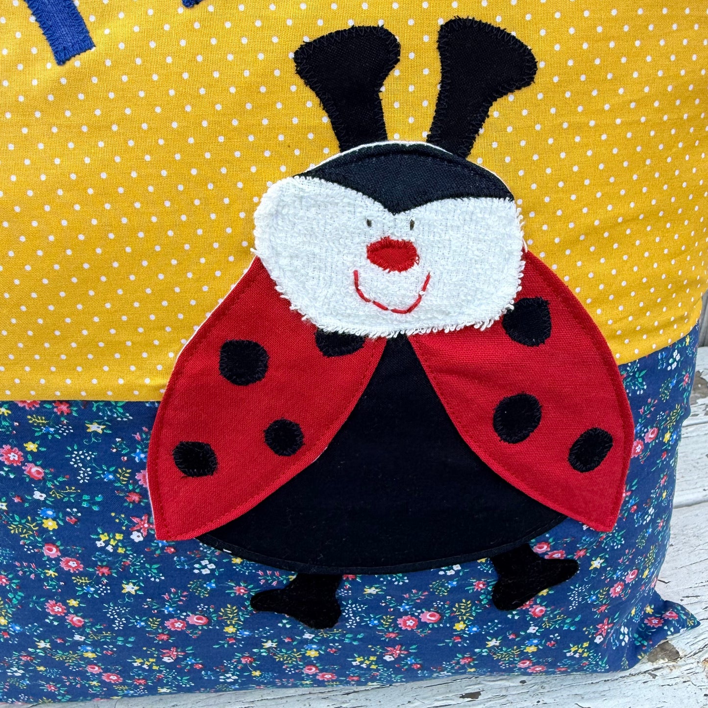 Kuschelkissen personalisiert Marienkäfer auf gelb gepunktet und blau geblümtem Baumwollstoff , Nahaufnahme der Marienkäfer Applikation