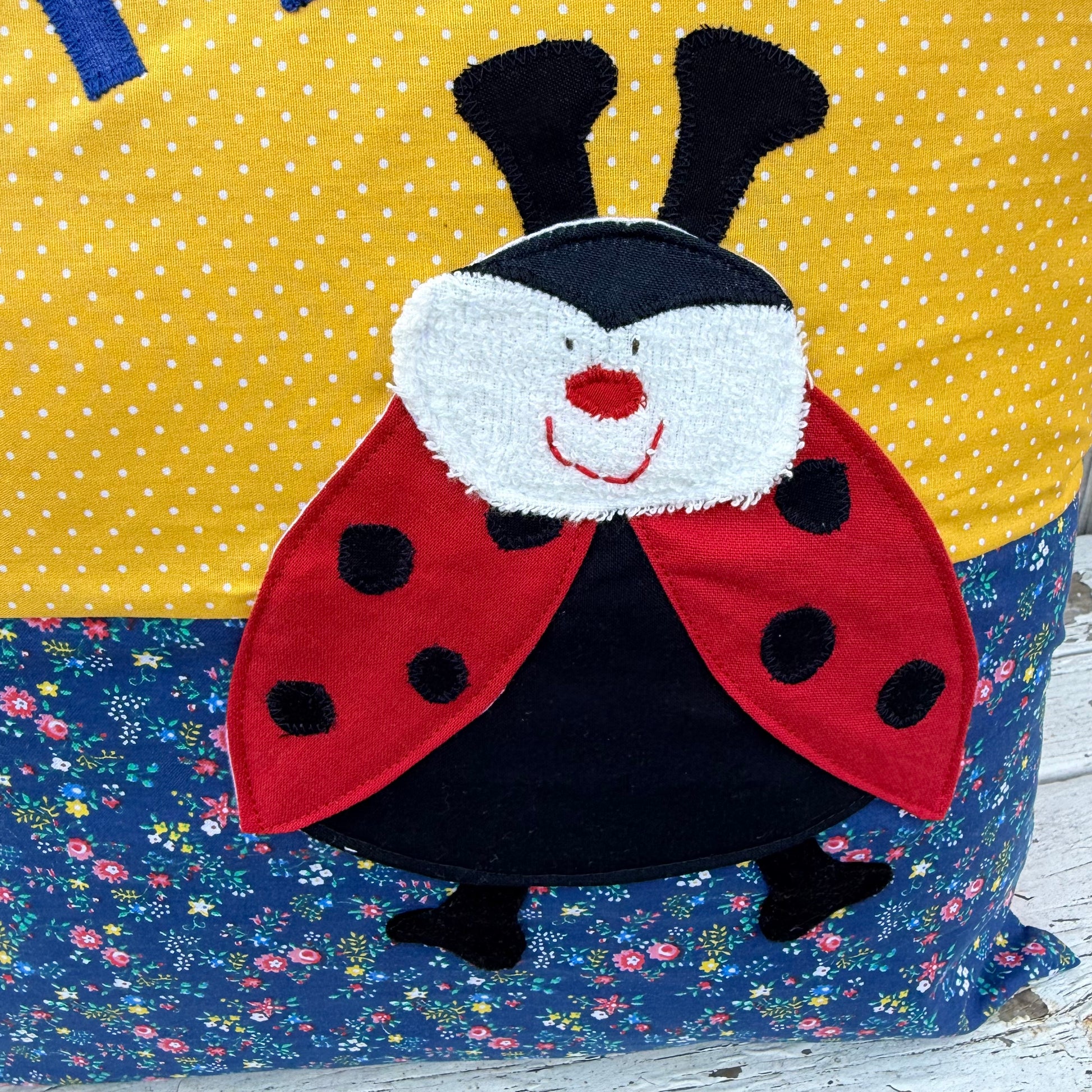 Kuschelkissen personalisiert Marienkäfer auf gelb gepunktet und blau geblümtem Baumwollstoff , Nahaufnahme der Marienkäfer Applikation