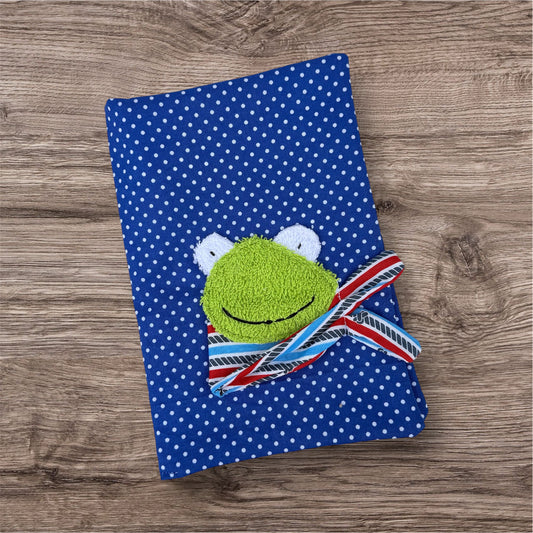 Personalisierbare U-Heft-Hülle aus royalblauen Stoff mit weißen Punkten , verziert mit einem fröhlichen Frosch und personalisierbar mit Namen