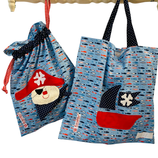 Handgemachtes Kita-Set bestehend aus einem blauen Wetbag mit Piratenmotiv und einem passenden Garderobenbeutel mit Piratenbootapplikation-beide aus maritimen  Stoff mit Sardinenprint und mit bunten Details